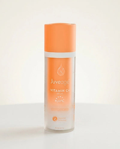 A bottle of Juveage Vitamin C Serum with a bright orange cap and a frosted glass body showing the orange liquid inside, set against a clean white background.
